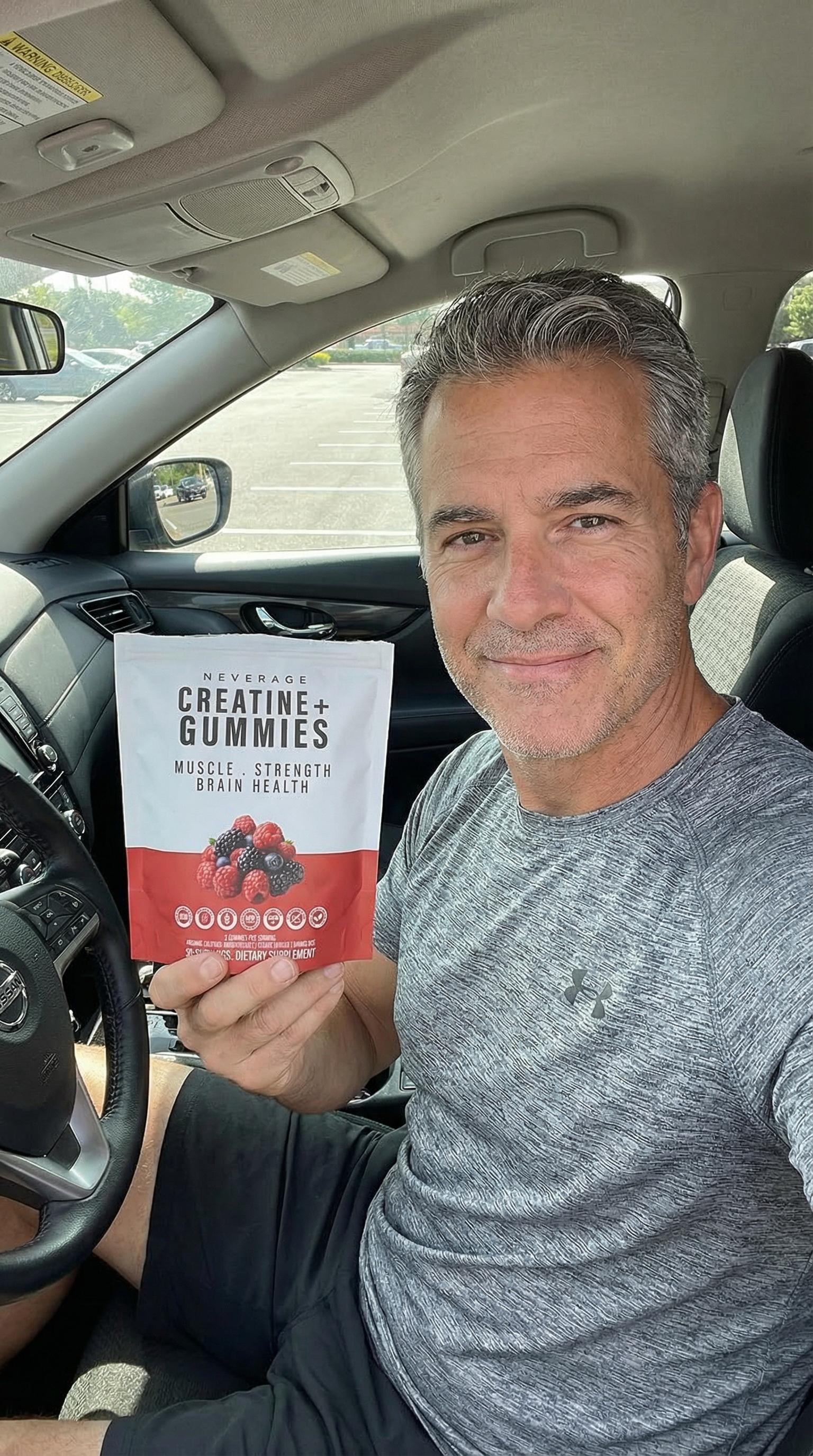 Man sitting in a car holding a creatine supplement package